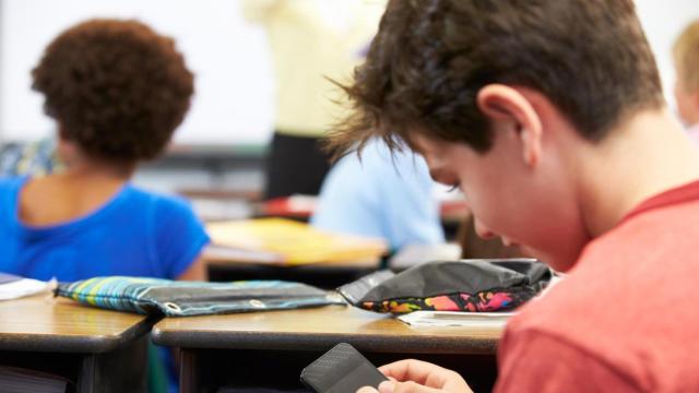 Un niño saca su teléfono en la escuela.